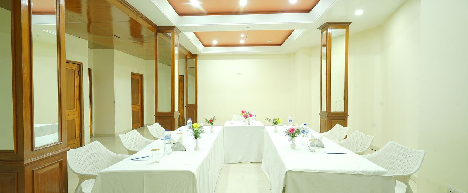 Conference hall with chairs and tables arranged under white lighting at DLS Hotels The Rock Castle.